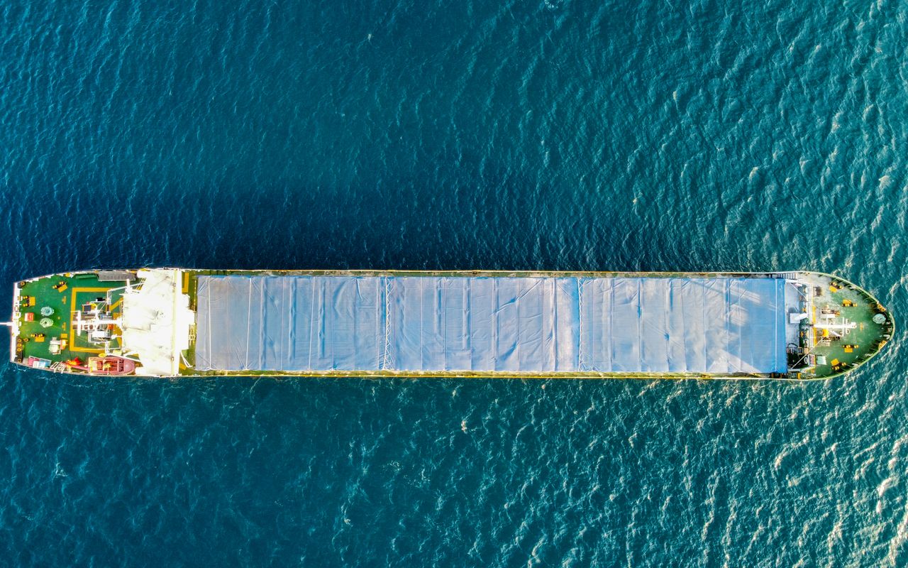 Illustrative stock photo: A cargo vessel viewed from above on blue-green water.